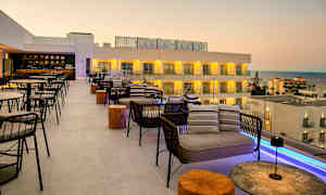 Tagterrasse med siddepladser og udsigt over havet og hotelbygninger. (AI-genereret tekst)