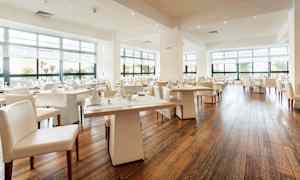 En moderne og lys restaurant med store vinduer og dækkede borde. (AI-genereret tekst)