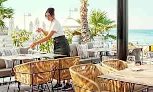 Udendørsservering ved havet med palmer i baggrunden. (AI-genereret tekst)