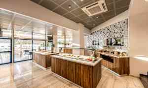 Et moderne og lyst buffetområde med mad serveret på træstationer og en dekoreret flisevæg. (AI-genereret tekst)