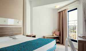 Hotelværelse med en opslået seng, natbord og en altandør. (AI-genereret tekst)