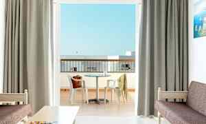 Et hotelværelse med udsigt til en altan med et bord og stole. (AI-genereret tekst)