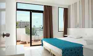 Et hotelværelse med en dobbeltseng, et vindue og en altan med siddepladser. (AI-genereret tekst)