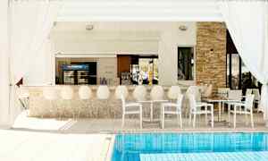 Udendørs bar med hvide stole og borde ved en pool. (AI-genereret tekst)