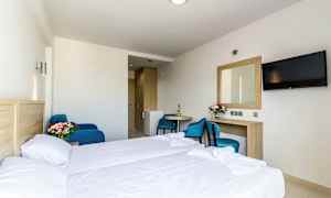 Hotelværelse med seng, bord, stol, spejl og TV. (AI-genereret tekst)