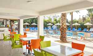 Udendørs servering med farverige stole foran en pool med liggestole og parasoller. (AI-genereret tekst)