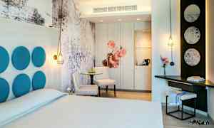 Et hotelværelse med moderne design, herunder en dobbeltseng, bord med stole og individuelle designdetaljer som dekorative paneler og belysning. (AI-genereret tekst)