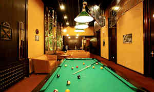 Spillerum med poolbord, sofaer og kunstnerisk indretning. (AI-genereret tekst)