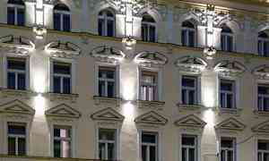 En facade på en bygning med flere vinduer, dekorationer og belysning om aftenen. (AI-genereret tekst)