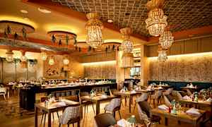 En restaurant med moderne møbler og dekorative lamper i loftet. (AI-genereret tekst)