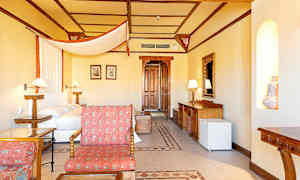 Et hotelværelse med møbler i træ, en seng med hvid og orange baldakin og en dekorativ væg-niche. (AI-genereret tekst)