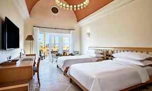 Hotelværelse med to enkeltsenge, skrivebord og siddeområde ved altanen. (AI-genereret tekst)