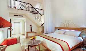 Moderne indrettet hotelsuite med dobbeltseng, siddeområde og trappe til hems. (AI-genereret tekst)