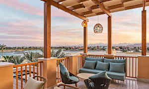 Terrasse med sofagruppe og udsigt over en kanal og bygninger i solnedgang. (AI-genereret tekst)