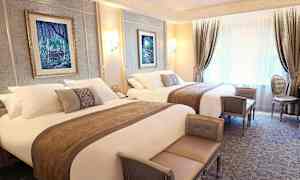 Luksuriøst indrettet hotelværelse med to dobbeltsenge, elegante møbler og vægdekorationer. (AI-genereret tekst)