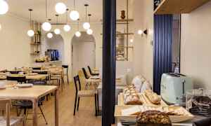 En spisesal med borde, stole og en buffet med brød og tilbehør. (AI-genereret tekst)