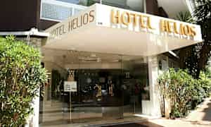 Indgangen til hotellet Hotel Helios med navnet skrevet over indgangen. (AI-genereret tekst)