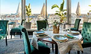 Restaurant med elegant borddækning og udsigt over byen. (AI-genereret tekst)