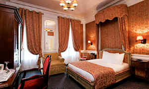 Et hotelværelse med klassisk indretning, der har en dobbeltseng, røde gardiner og en lænestol. (AI-genereret tekst)