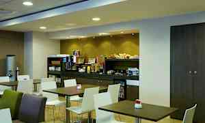 Morgenmadsrum med borde og stole samt en buffet med forskellige madvarer. (AI-genereret tekst)