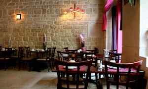 Et restaurantområde med borde og stole samt dekorationsplanter foran en murstensvæg. (AI-genereret tekst)