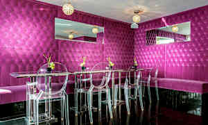 En moderne og farverig restaurant eller lounge med fuchsiafarvede vægpaneler, gennemsigtige stole og spejldekorationer. (AI-genereret tekst)