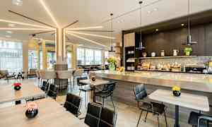 Moderne cafémiljø med siddepladser ved borde og bardisk, dekoreret med blomster. (AI-genereret tekst)