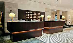 En receptionsskranke i en hotellobby med marmorbordplader og bordlamper. (AI-genereret tekst)