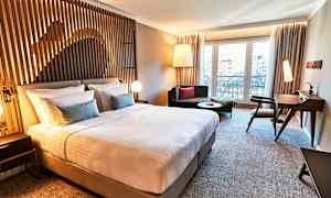 Et moderne hotelværelse med en stor seng, siddepladser og skrivebord. (AI-genereret tekst)