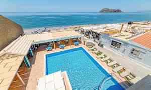 Billede af en udendørs pool med liggestole, restaurantområde og havudsigt i baggrunden. (AI-genereret tekst)