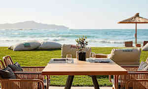 Et bord med stole på en terrasse med udsigt over havet. (AI-genereret tekst)