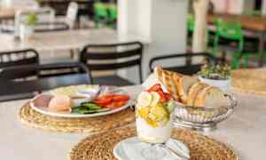 En morgenmad med frisk frugt i et glas, brød og pålæg på en tallerken. (AI-genereret tekst)