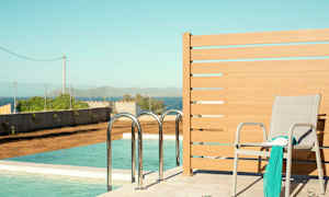 En solstol med et sjal og en bog står ved siden af en pool med havudsigt. (AI-genereret tekst)