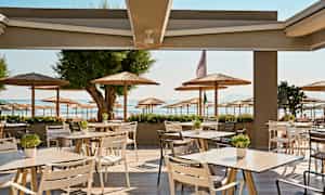 Udendørs serveringsområde med udsigt til en strand og parasoller. (AI-genereret tekst)