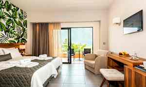 Et hotelværelse med dobbeltseng, siddegruppe, altan og vægdesign med bladmotiv. (AI-genereret tekst)