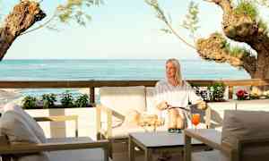 En siddegruppe ved havet med udsigt over blåt vand og træer. (AI-genereret tekst)