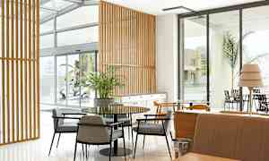 Interiør af et moderne rum med borde, stole og vinduer. (AI-genereret tekst)