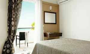 Hotelværelse med seng, spejl, gardiner og altan med havudsigt. (AI-genereret tekst)