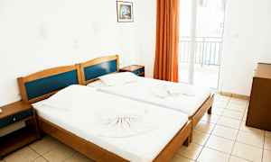 To enkeltsenge i et lyst rum med et billede på væggen og en altan med orange gardiner. (AI-genereret tekst)