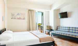 Et hotelværelse med en seng, en sofa, et fjernsyn og en altan. (AI-genereret tekst)