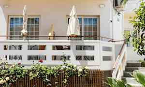 Terrasse med parasoller og havemøbler ved en lys bygning. (AI-genereret tekst)