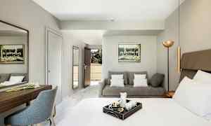 Et hotelværelse med en seng, en sofa og et skrivebord. (AI-genereret tekst)