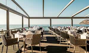 Restaurant med havudsigt, elegante møbler og dækkede borde. (AI-genereret tekst)