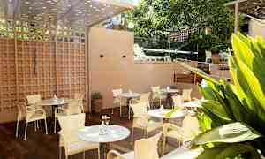 En terrasse med borde og stole, omgivet af planter. (AI-genereret tekst)