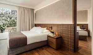 Hotelværelse med dobbeltseng, natbord og garderobe. (AI-genereret tekst)