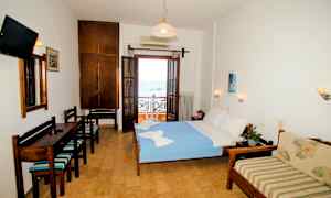 Et hotelværelse med en seng, en sofa og et skrivebord. Værelset har en balkon med udsigt over havet. (AI-genereret tekst)