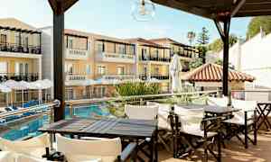 Hotelbygning med altaner og parasoller ved poolen, med siddegrupper i forgrunden. (AI-genereret tekst)
