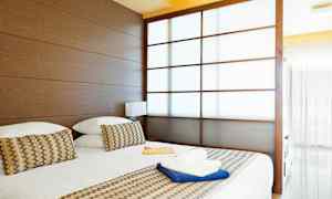 Et hotelværelse med en stor seng, træpaneler og en delvist gennemsigtig skydedør. (AI-genereret tekst)