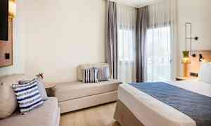 Moderne hotelværelse med seng, sofa og vinduer med lyse gardiner. (AI-genereret tekst)