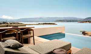 Terrasse med pool og udsigt over hav og bjerge. (AI-genereret tekst)